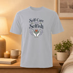 Gray t-shirt with "Self-Care Isn't Selfish" text and illustrated hands holding a plant.