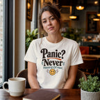 Woman wearing cream t-shirt with "Panic? Never" and smiley face.
