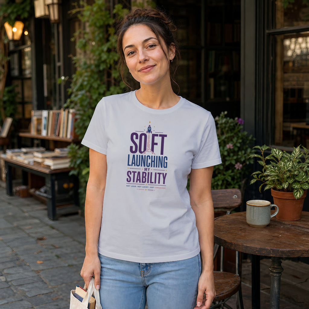 Woman wearing white t-shirt with "Soft Launching My Stability" text.