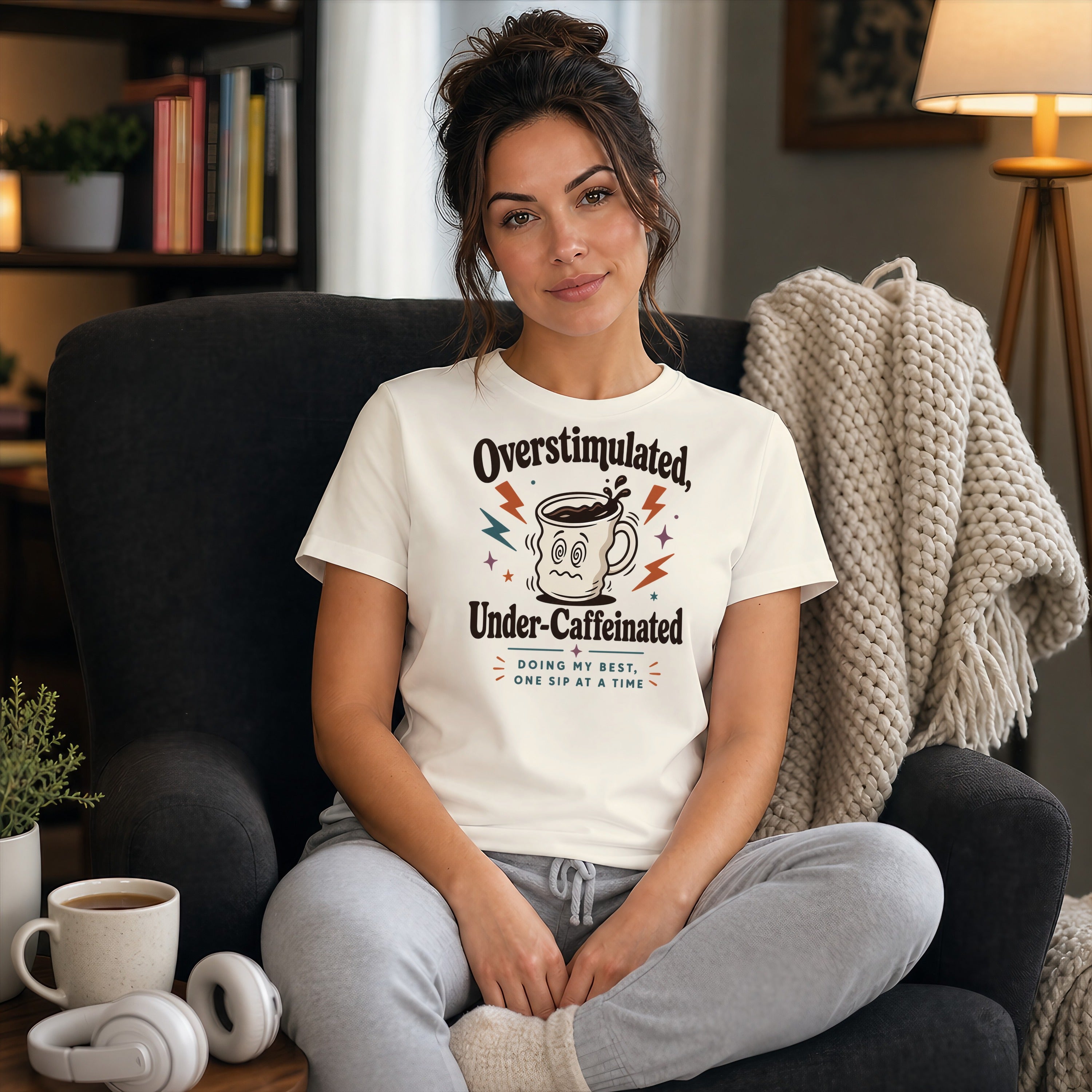 Woman in t-shirt with "Overstimulated, Under-Caffeinated" text, sitting in chair.