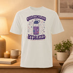 White t-shirt with "Overstimulated but Hydrated" text and a decorated water bottle graphic.