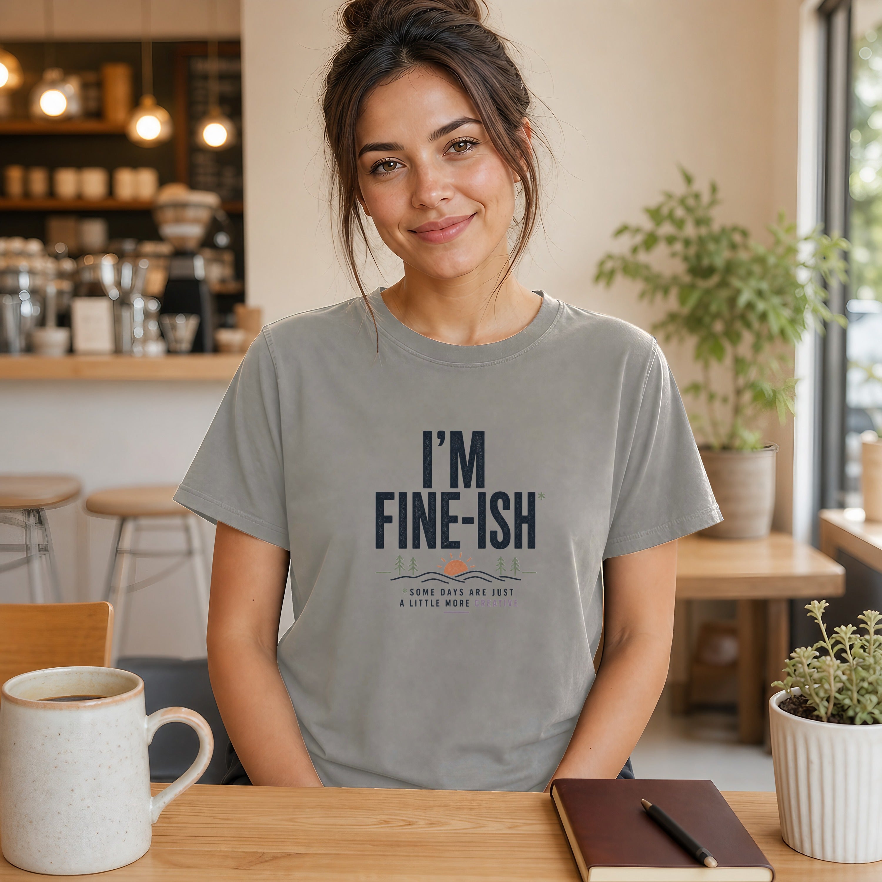 Woman wearing gray t-shirt with "I'm Fine-ish" text and sunset graphic.