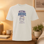 White t-shirt with "Resting Anxious Face" text and anxious emoji graphic.