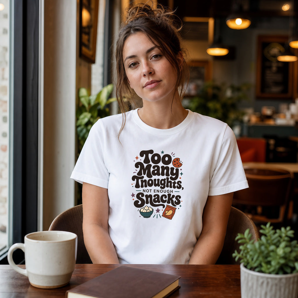 Woman wearing a white t-shirt with "Too Many Snacks, Not Enough" text.