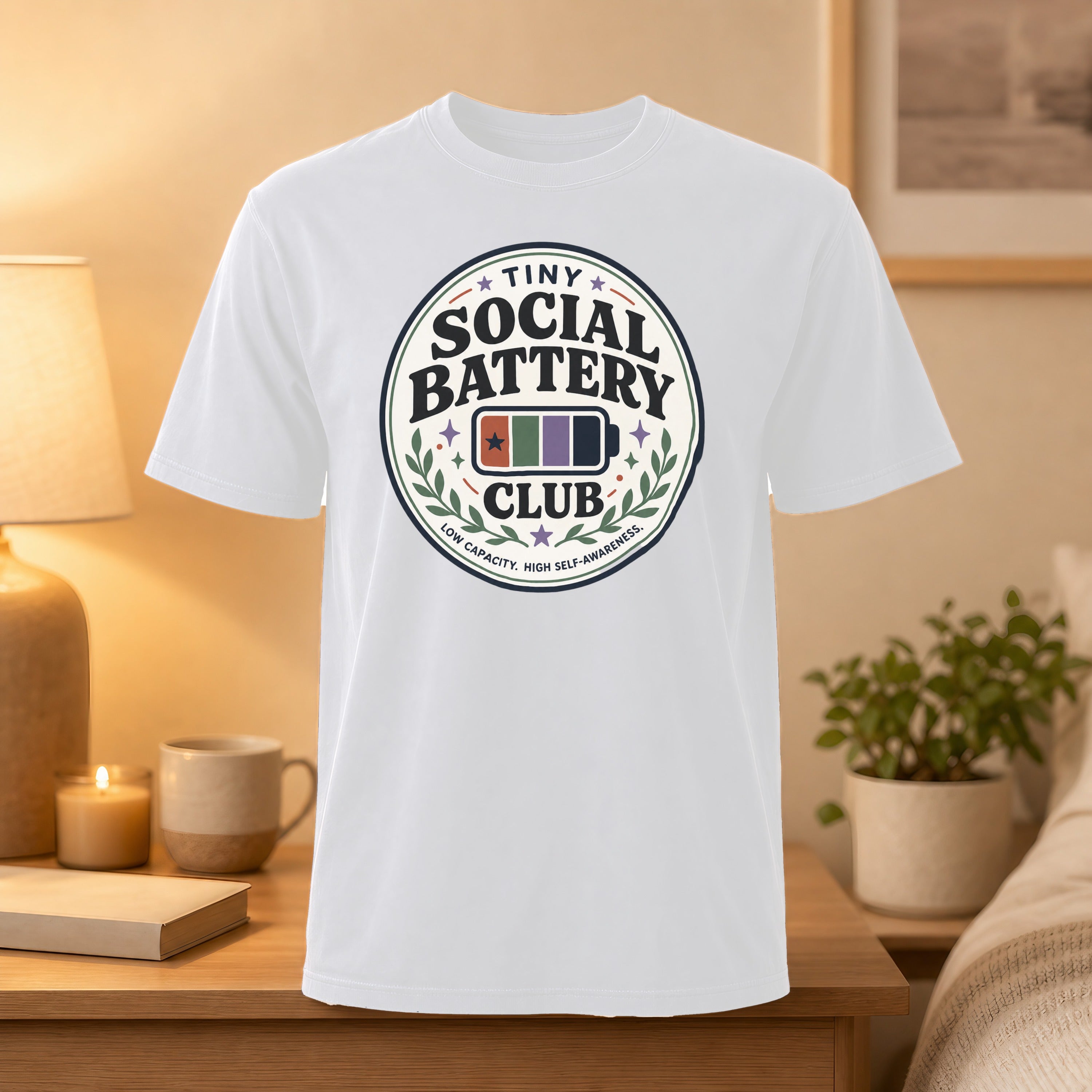 White t-shirt with "Tiny Social Battery" circular logo, featuring stars and battery icon.