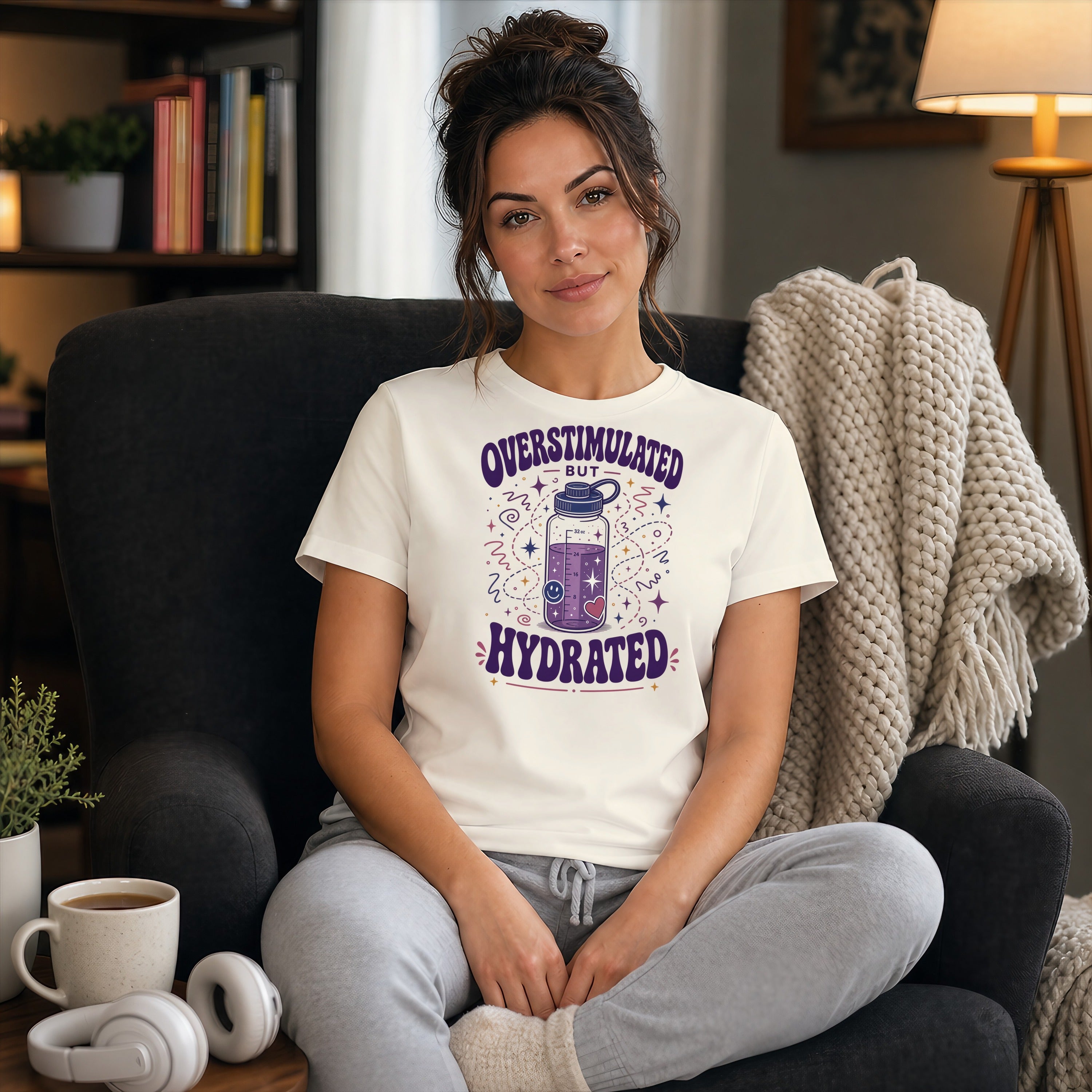 Woman in t-shirt with "Overstimulated but Hydrated" graphic sitting in armchair.