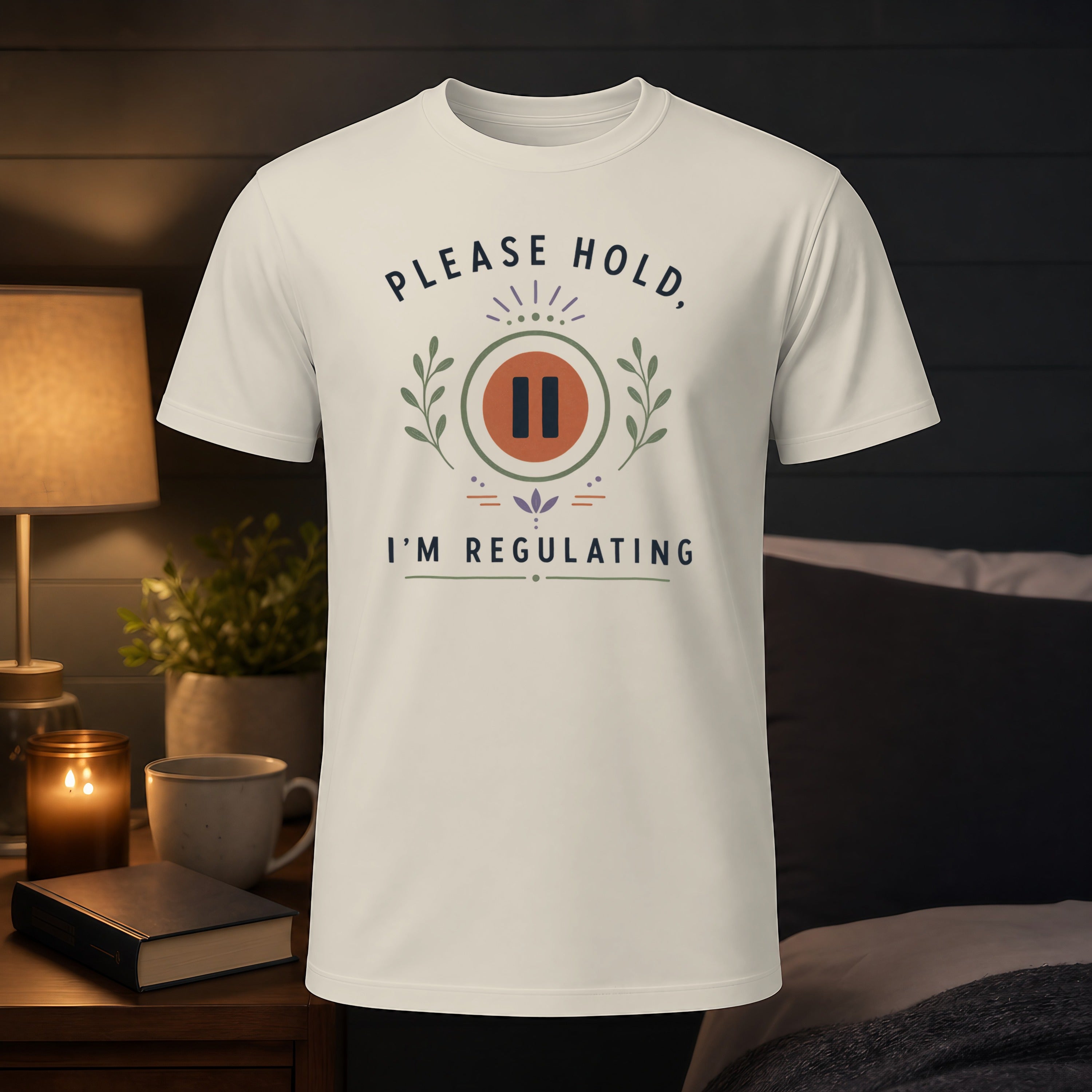 Cream t-shirt with "PLEASE HOLD, I'M REGULATING" text and pause symbol.