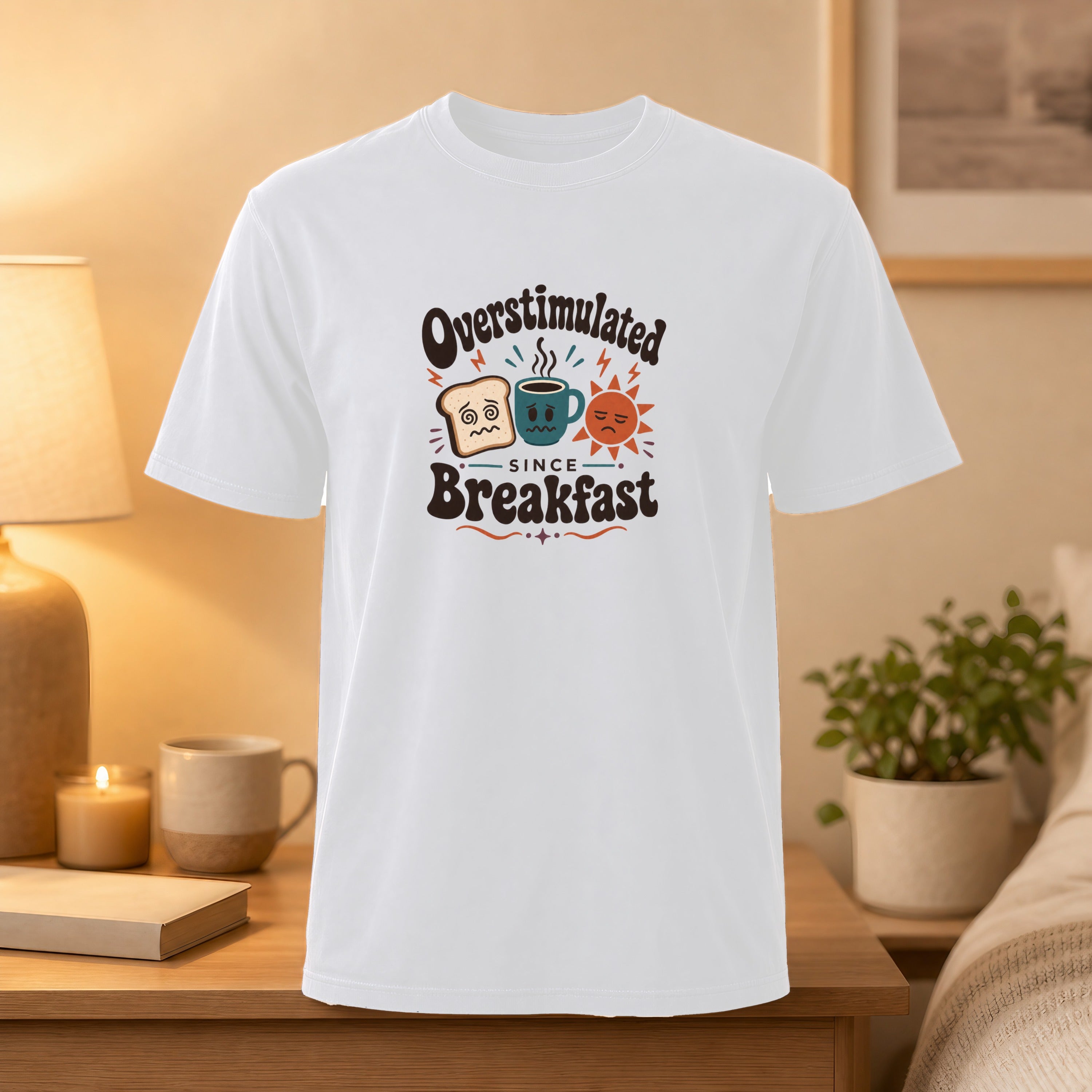 White t-shirt with "Overstimulated Since Breakfast" graphic featuring worried toast and coffee.