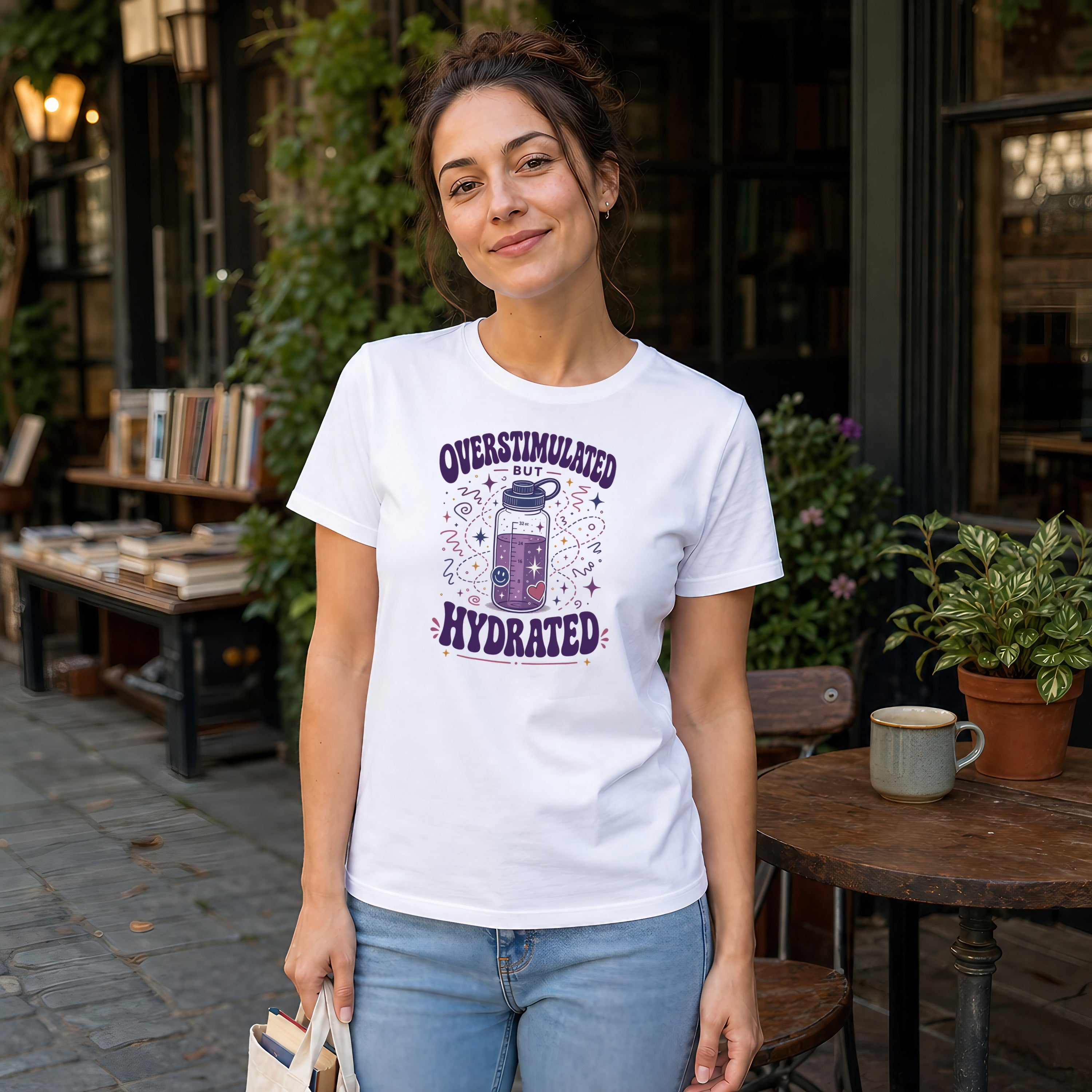 Woman wearing white t-shirt with "Overstimulated but Hydrated" graphic.