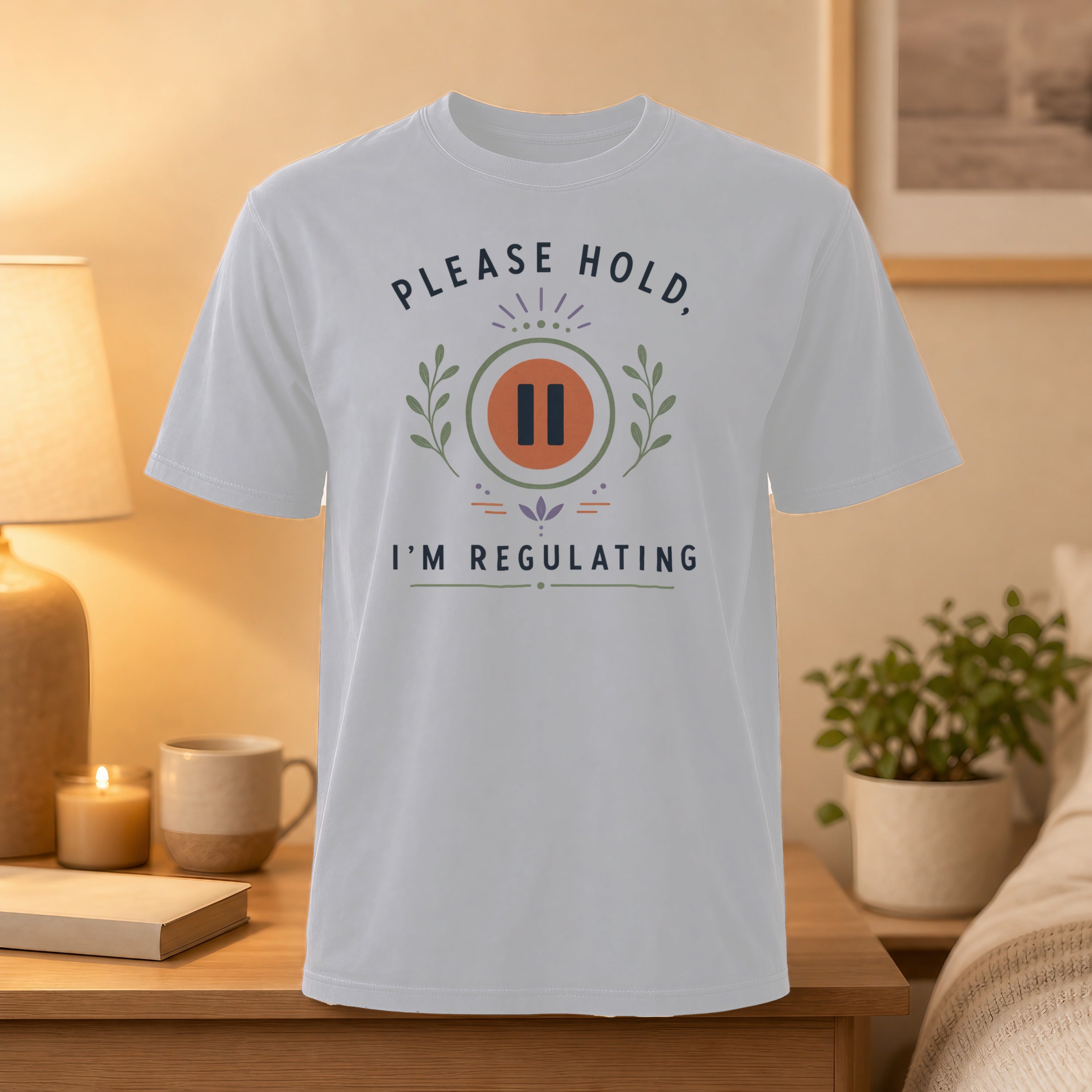 White t-shirt with "PLEASE HOLD, I'M REGULATING" text and laurel leaf graphic.