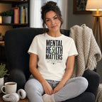 Woman in armchair wearing "Mental Health Matters" t-shirt with green ribbon.