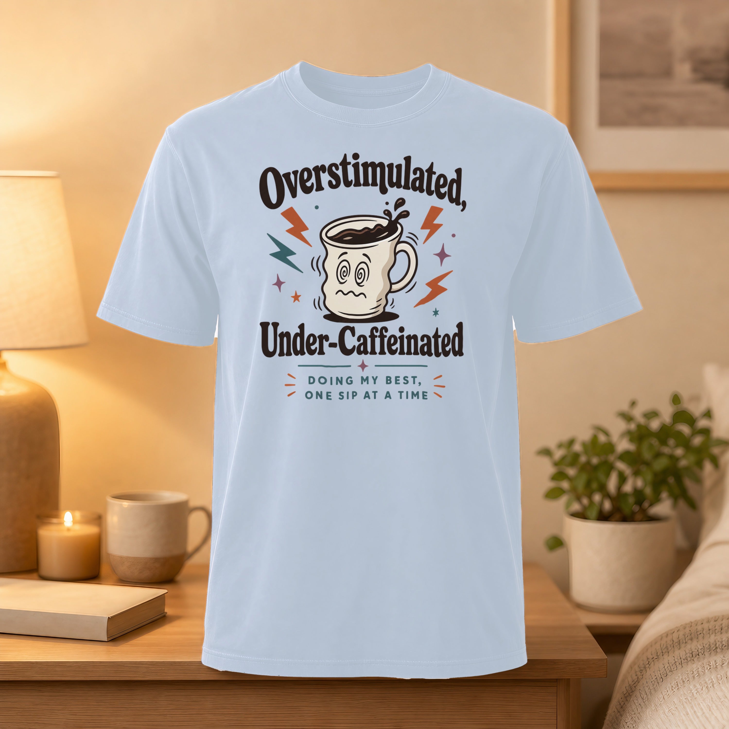 Light blue t-shirt with "Overstimulated, Under-Caffeinated" text and a coffee cup graphic.