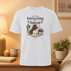 White t-shirt with "Introverting With Intent" text and cozy reading nook graphic.