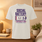 White t-shirt with "Social Battery: Critically Low 2%" and a battery icon.