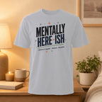 White t-shirt with "MENTALLY HERE-ISH PHYSICALLY... BUFFERING." text.