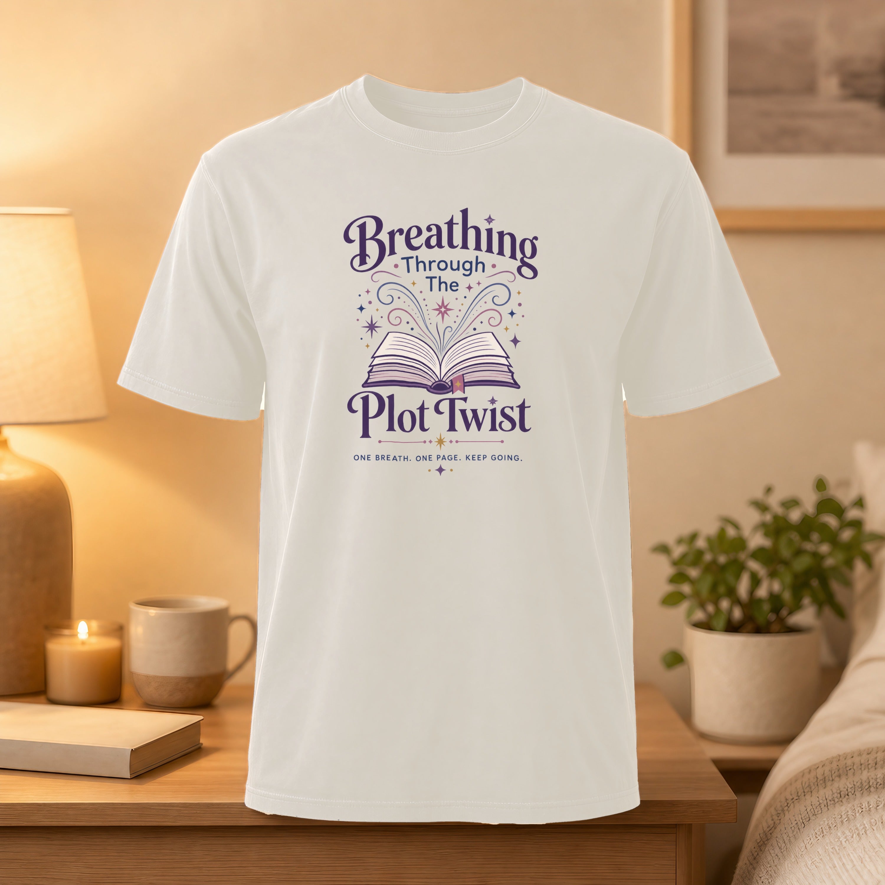 White t-shirt with "Breathing Through the Plot Twist" text and open book graphic.