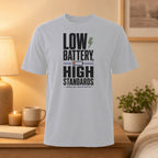 White t-shirt with "LOW BATTERY, HIGH STANDARDS. ENERGY LOW, EXPECTATIONS NOT."