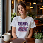 Woman wearing white t-shirt with text "Overstimulated but still cute".