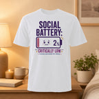 White t-shirt with "SOCIAL BATTERY: CRITICALLY LOW 2%" text and battery graphic.