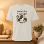 White t-shirt with "Introverting With Intent" text and cozy room illustration.