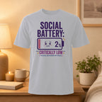White t-shirt with "SOCIAL BATTERY: 2% PLEASE RECHARGE MY SPACE" graphic.