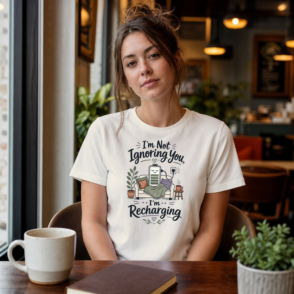 Woman wearing a "I'm Not Ignoring You, I'm Recharging" t-shirt with battery graphic.